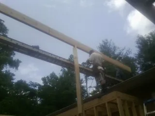 Carpenter setting a ridge beam over a new addition frame — Ice Dam Removal by Roofing Brothers in Bryceville