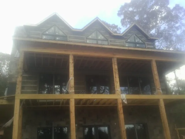 Dormers and porch framing on a large log home under construction — Roof Coating work by our crew in Bryceville