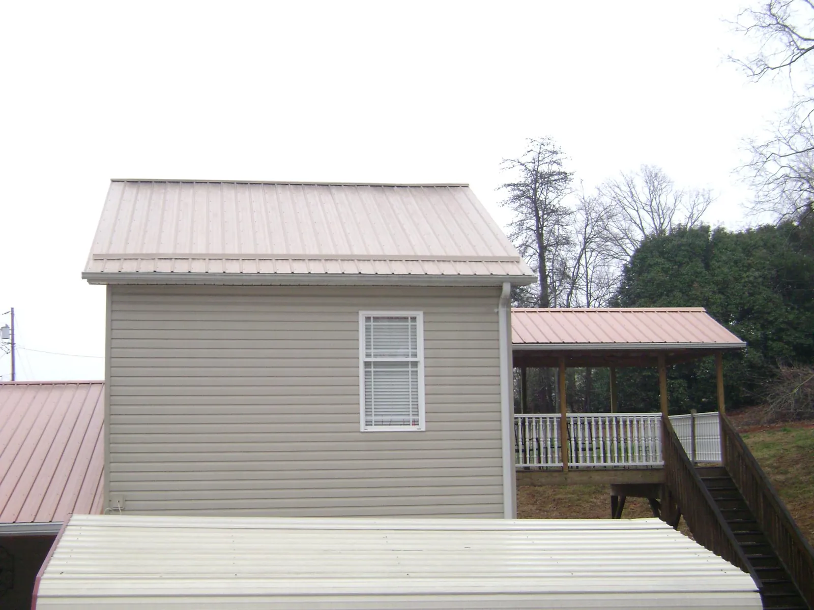 Tan metal roofs on a two story addition and attached porch, from a Roof Replacement job in Bryceville