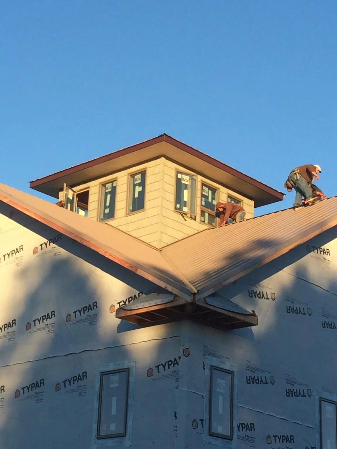 Roofers working around a rooftop cupola on a new metal roof at sunset — Roof Waterproofing in Bryceville by Roofing Brothers